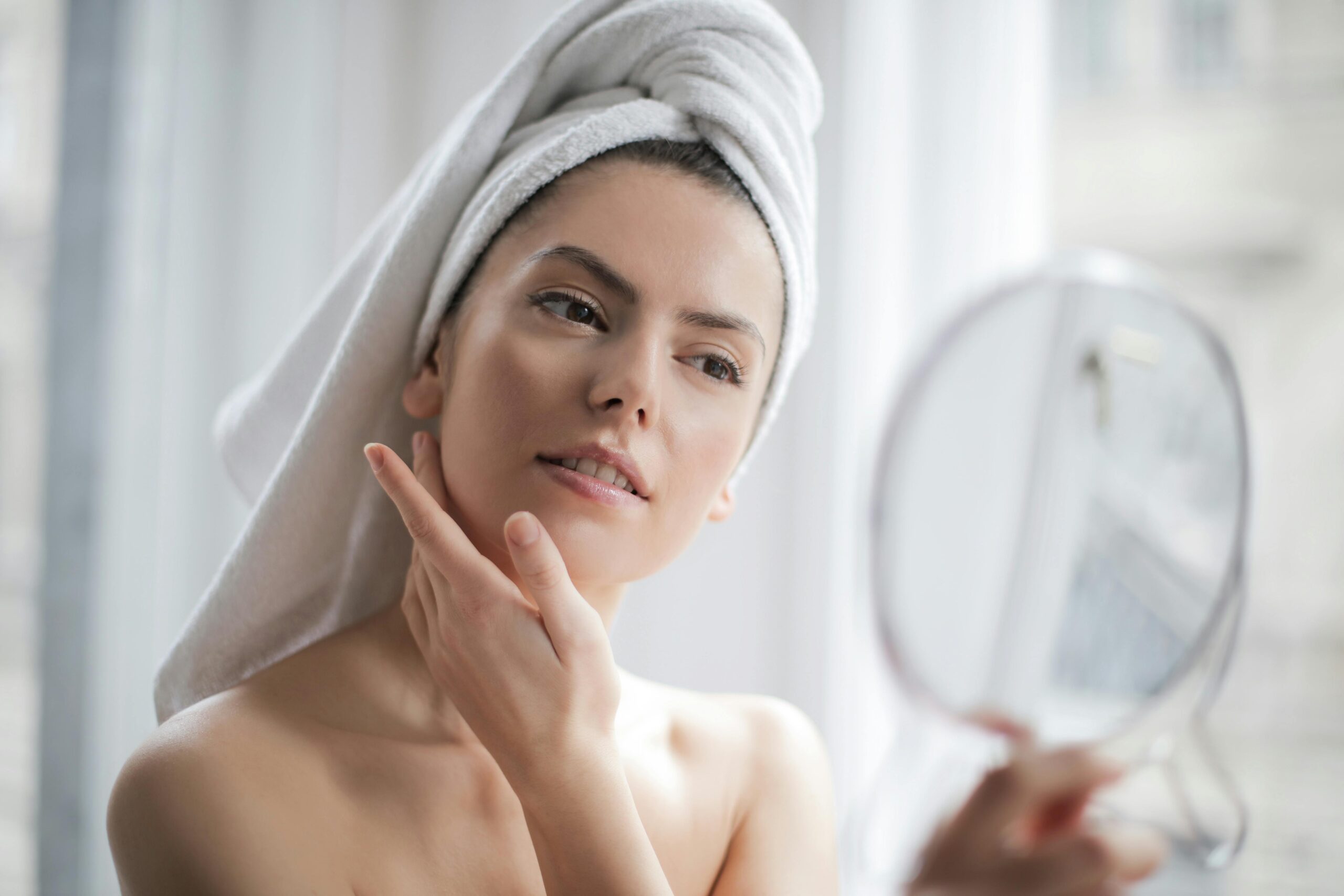 Woman applying moisturizer during fall season with autumn leaves in the background